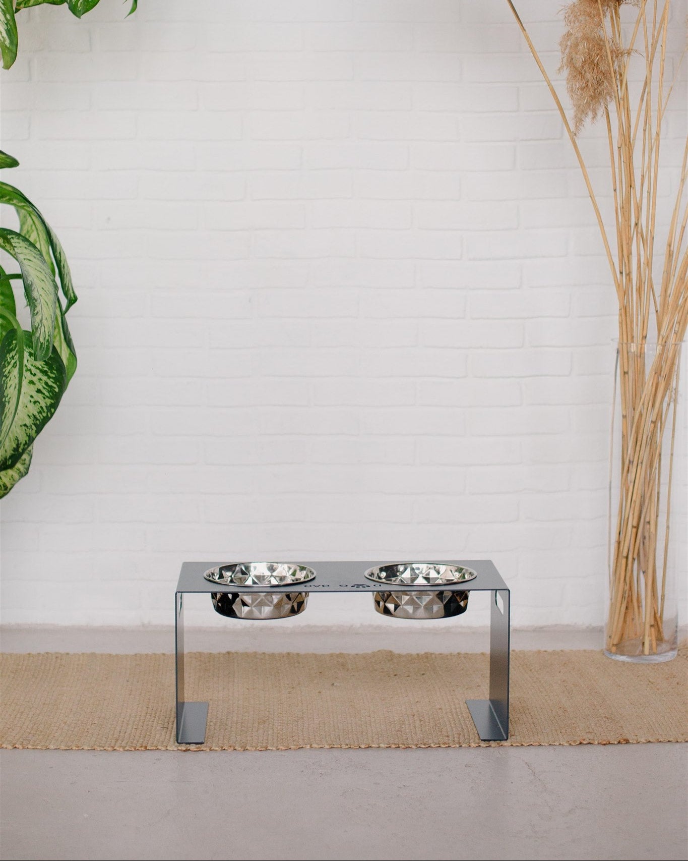 Chrome elevated pet feeder with two bowls on a white wall background
