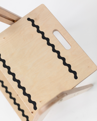 Wooden step stool with wavy black line design on a white background