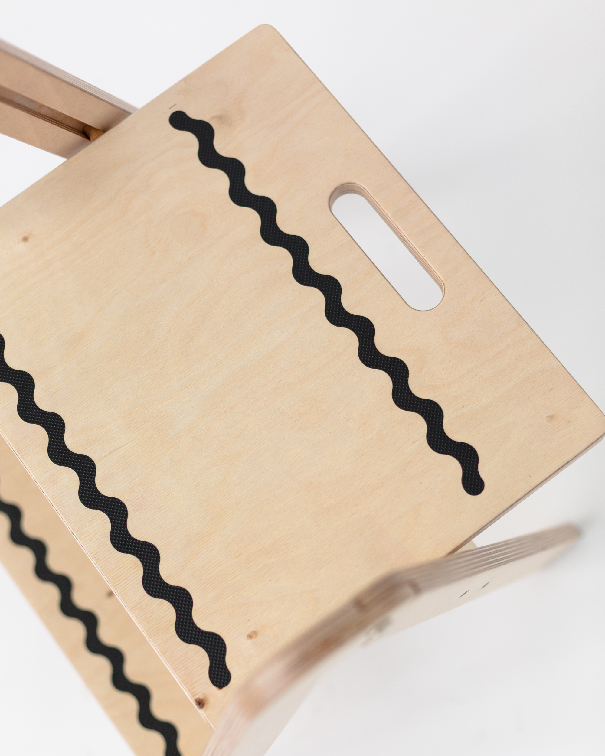 Wooden step stool with wavy black line design on a white background