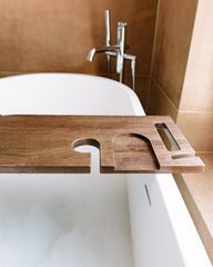 Wooden bathtub tray with faucet above a white bathtub in a bathroom setting