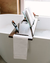 Bathroom setting with a bathtub, towel, and open book.