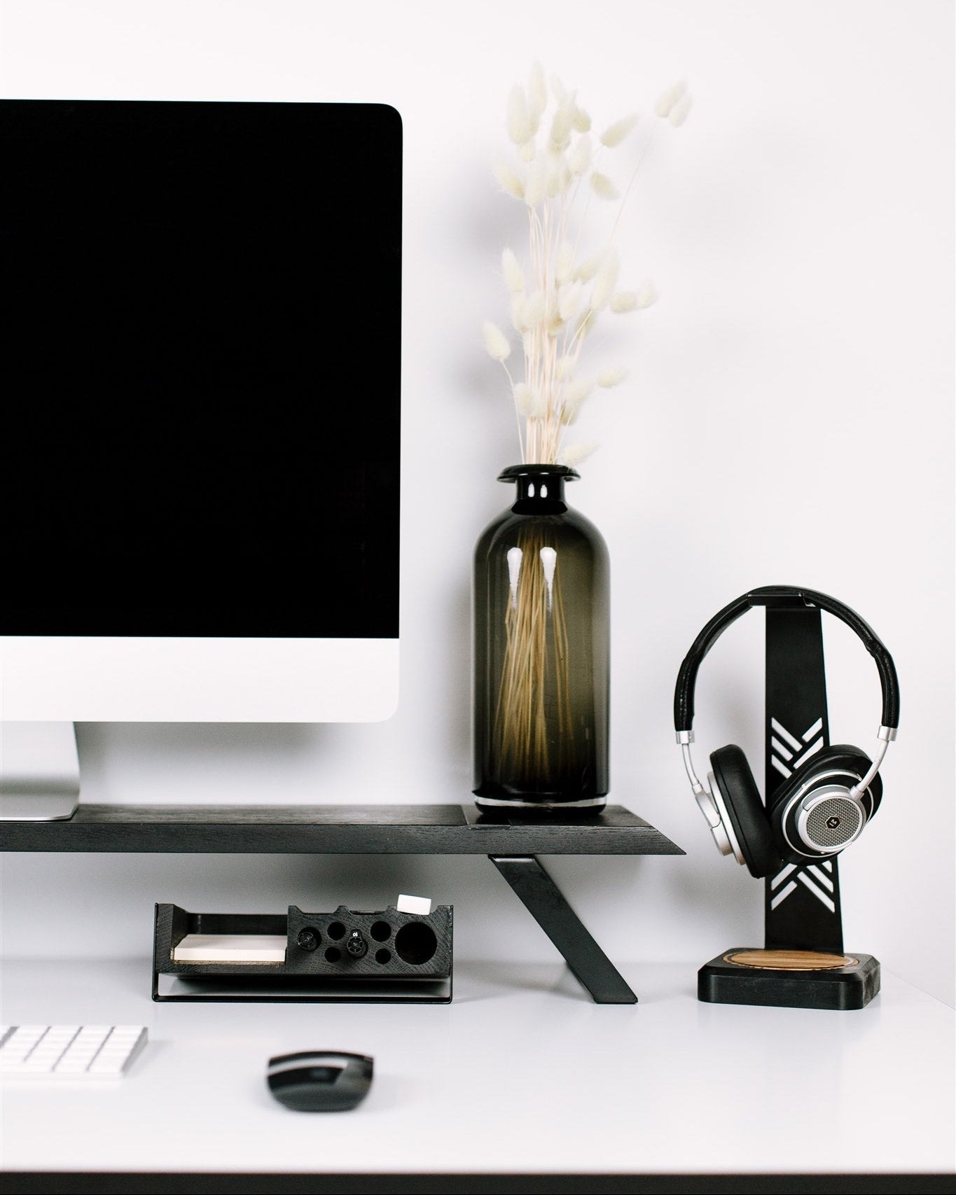 Modern office desk setup with computer monitor, keyboard, mouse, and decorative items.