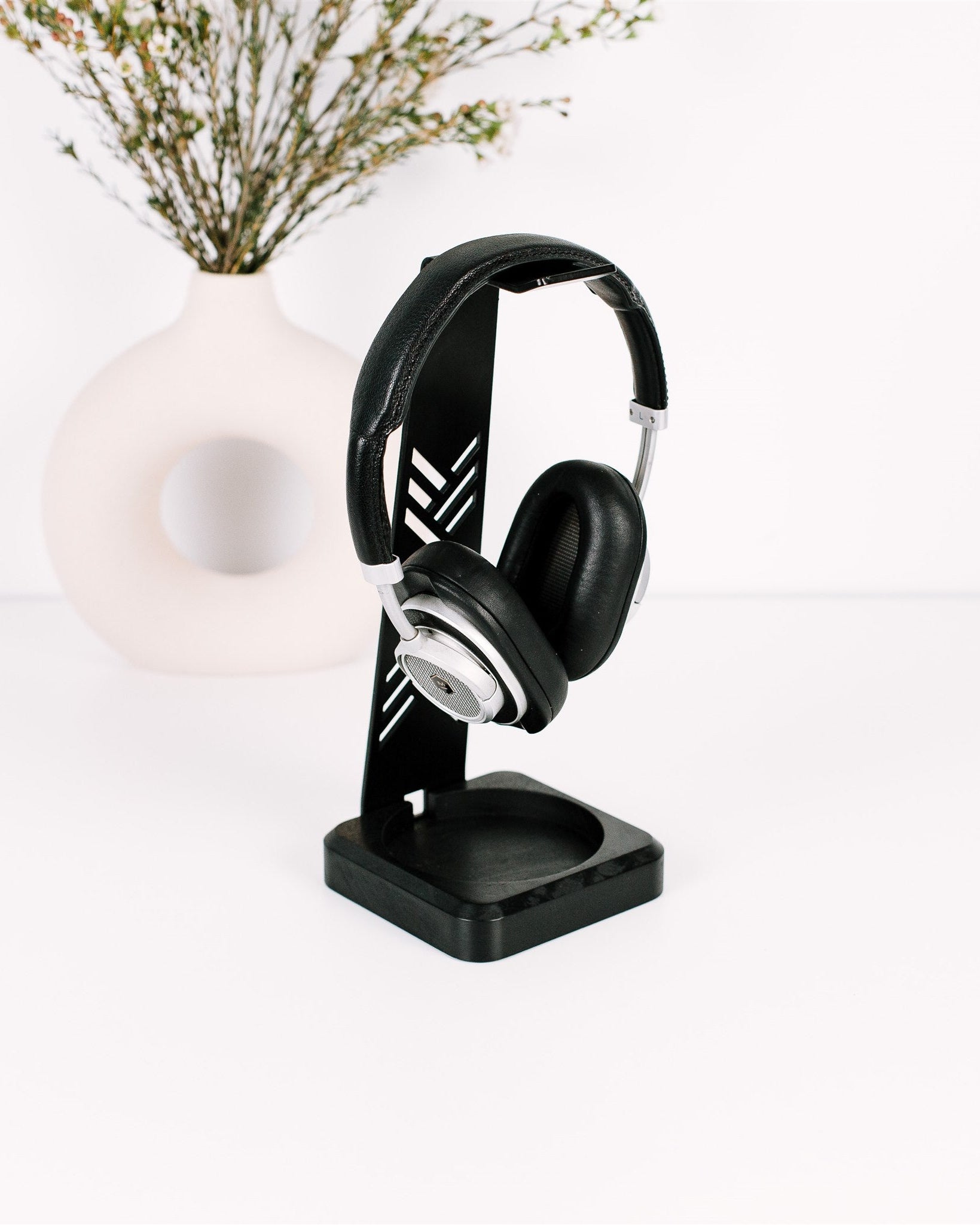 Black headphones on a stand with a white background