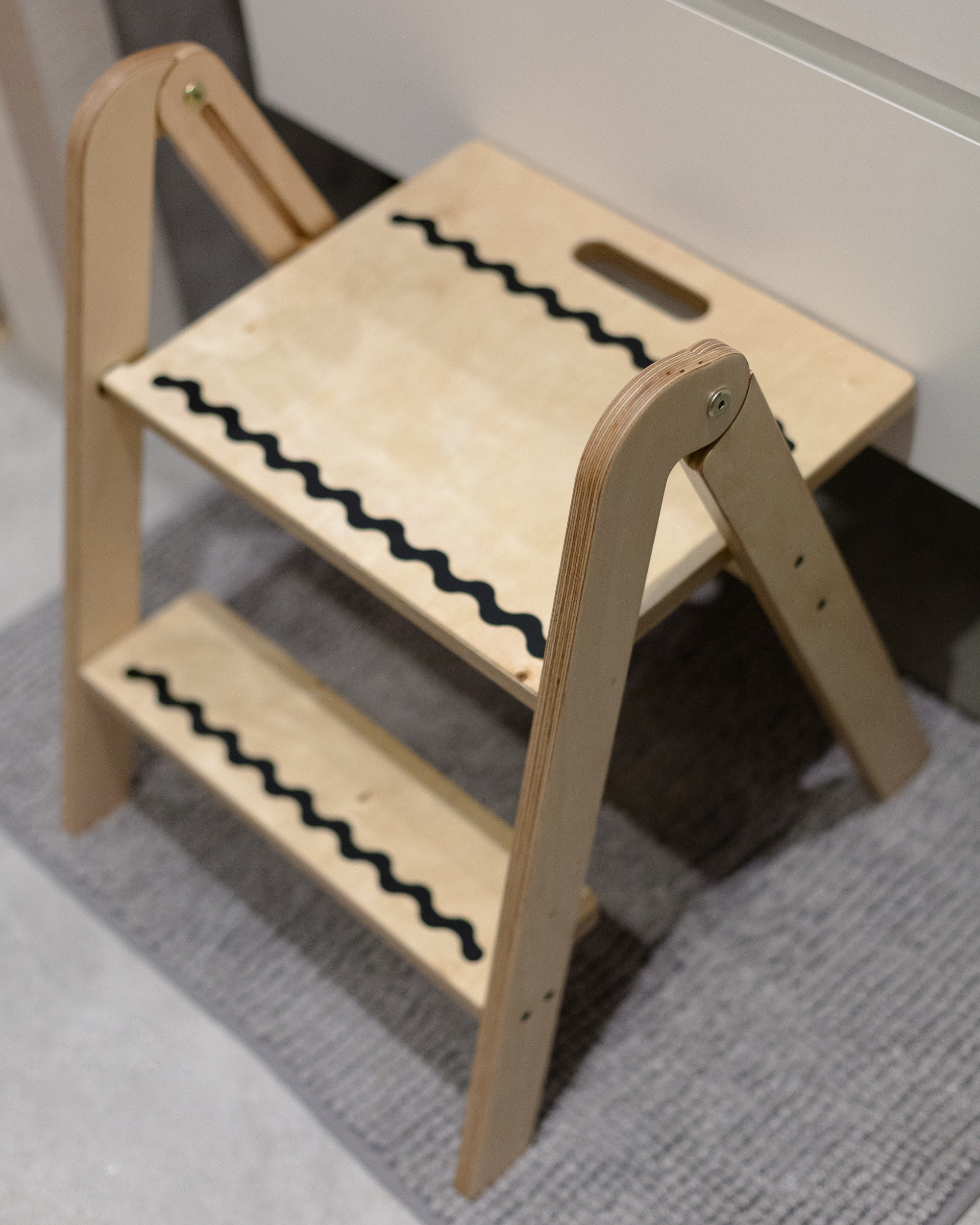 Wooden step stool with zebra pattern on a carpeted floor
