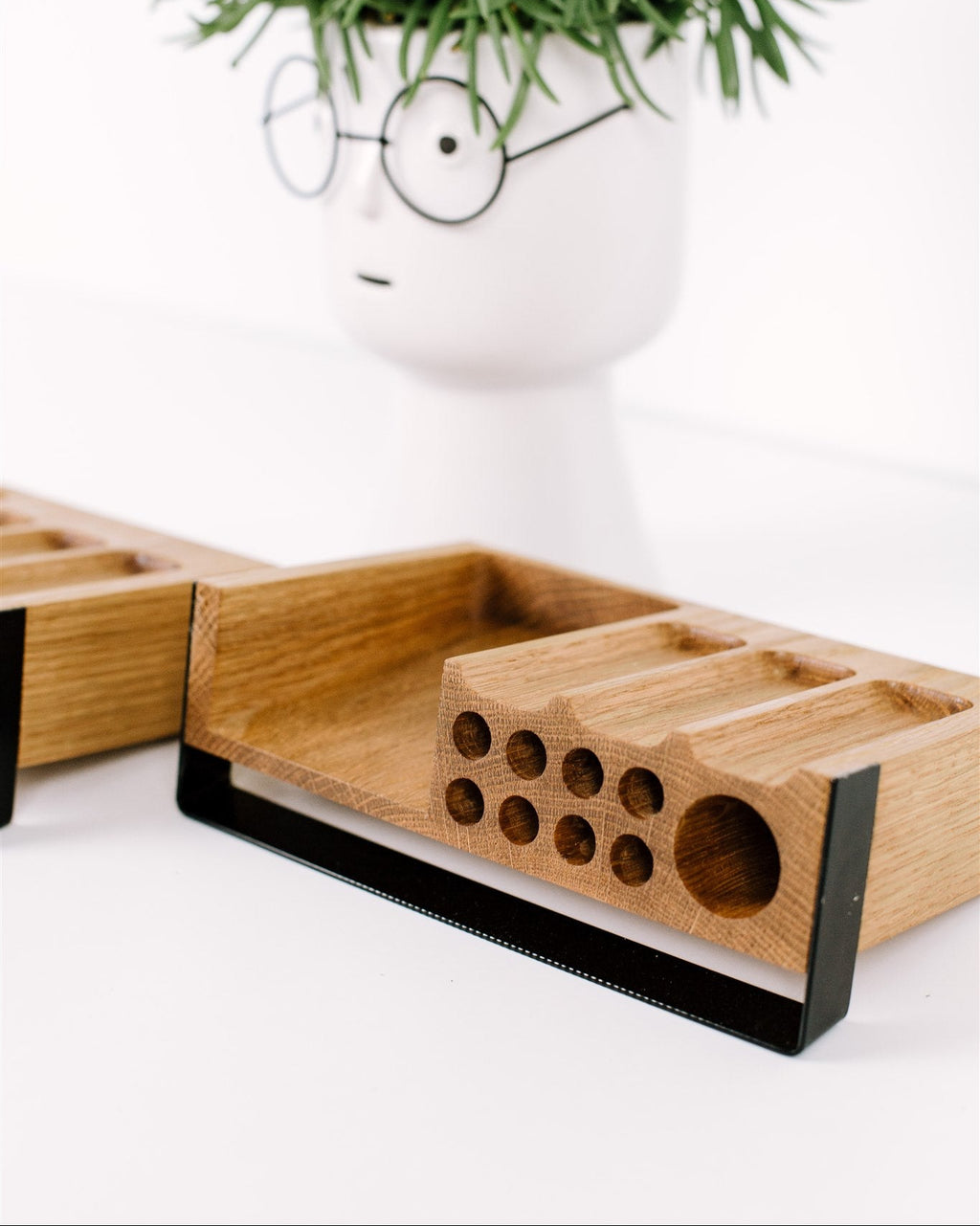 Wooden tray with geometric design on a white surface, featuring a plant in the background.