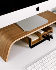 Wooden monitor stand with a computer setup on a white surface