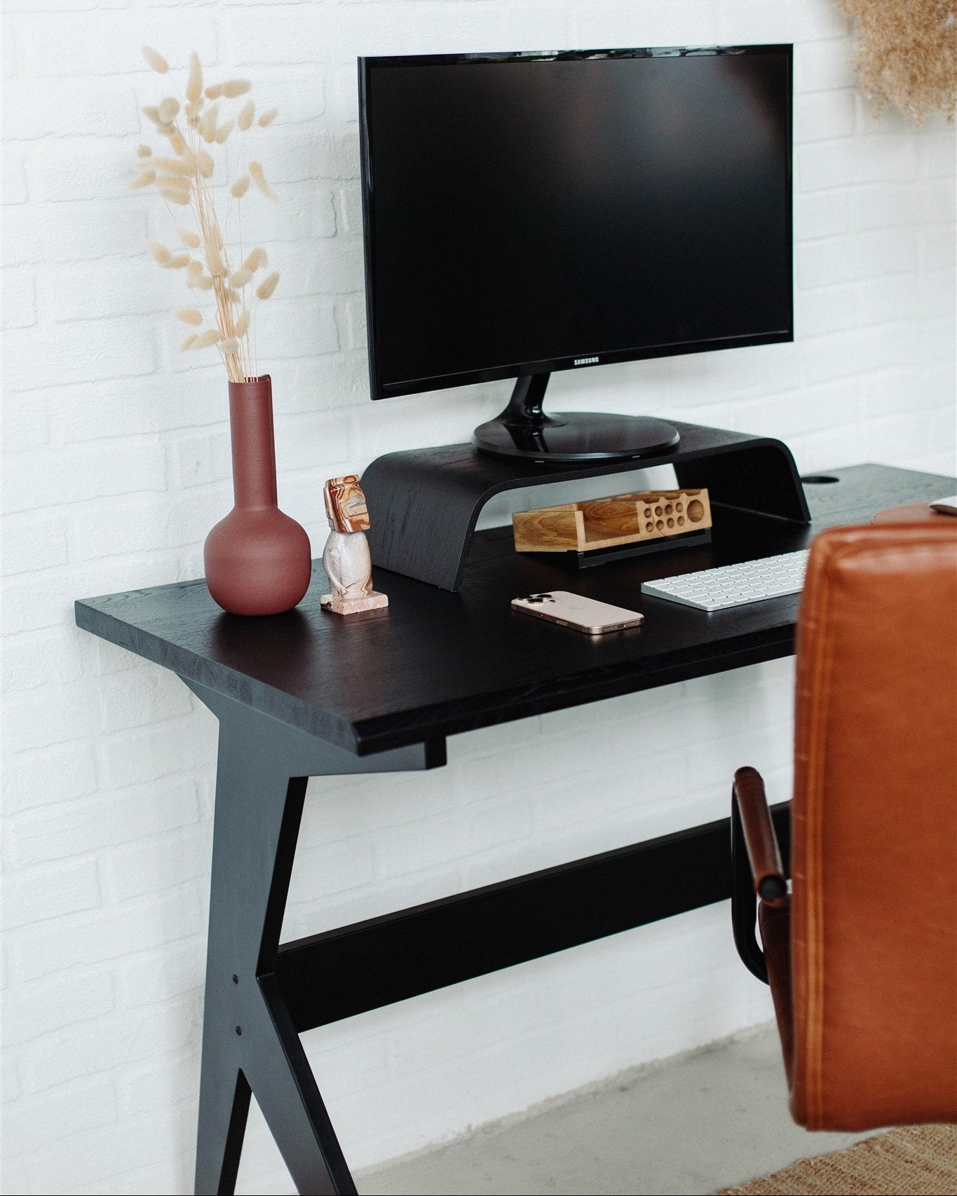 Black desk with a TV on a white brick wall background