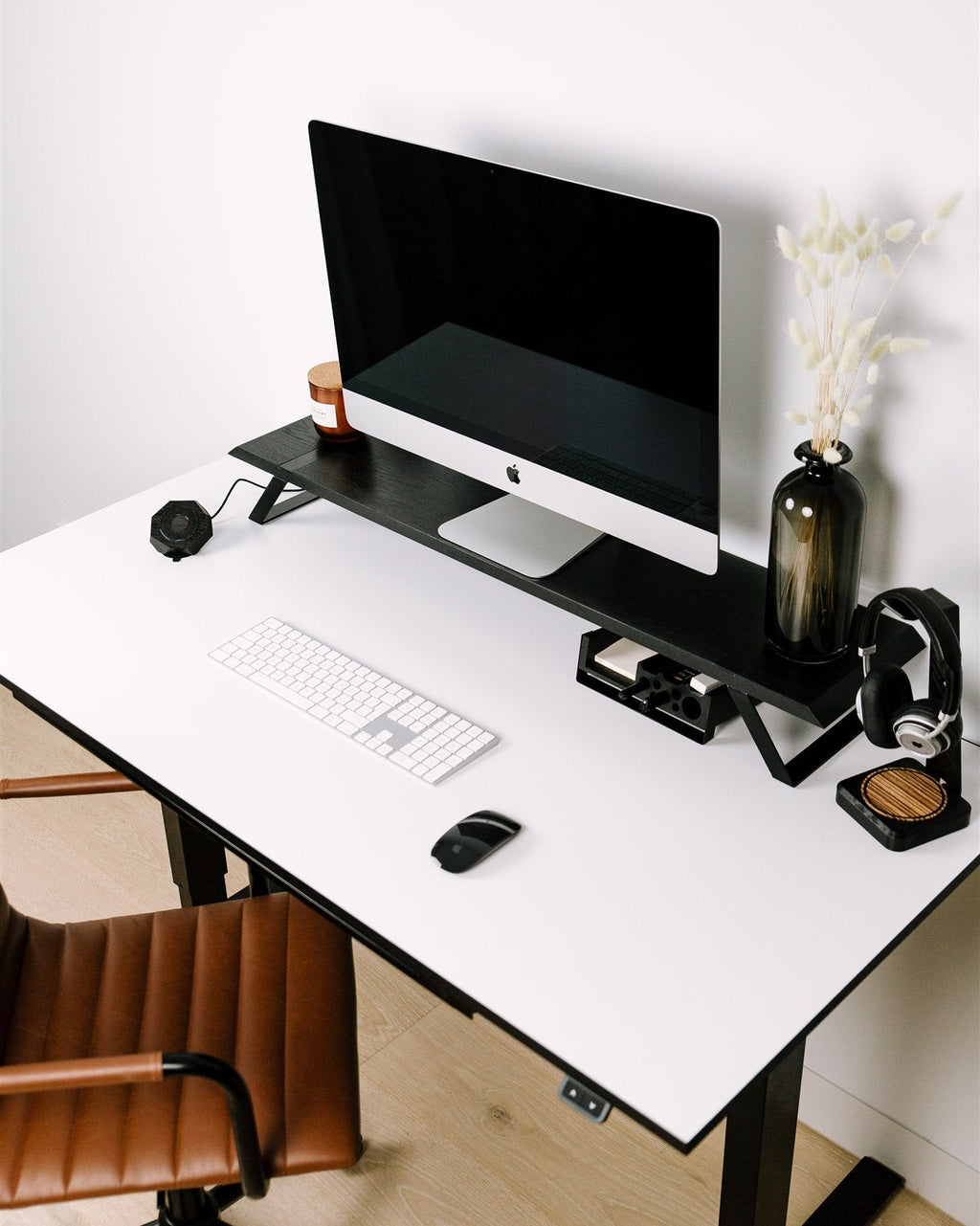 Modern home office desk with computer setup, chair, and decor.