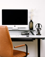 Modern office desk with computer monitor, chair, and decor items.