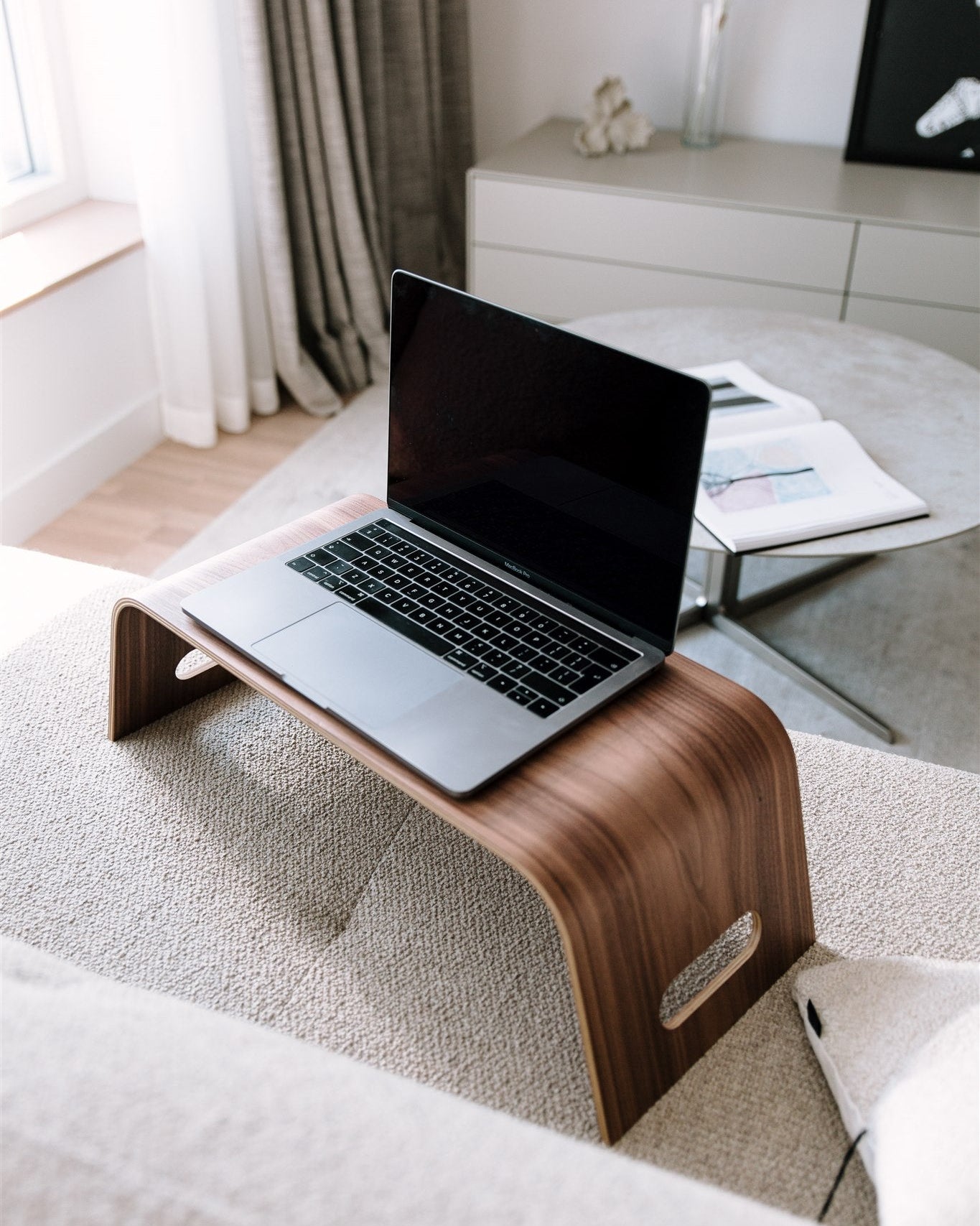 Laptop on a wooden stand in a cozy living room setting