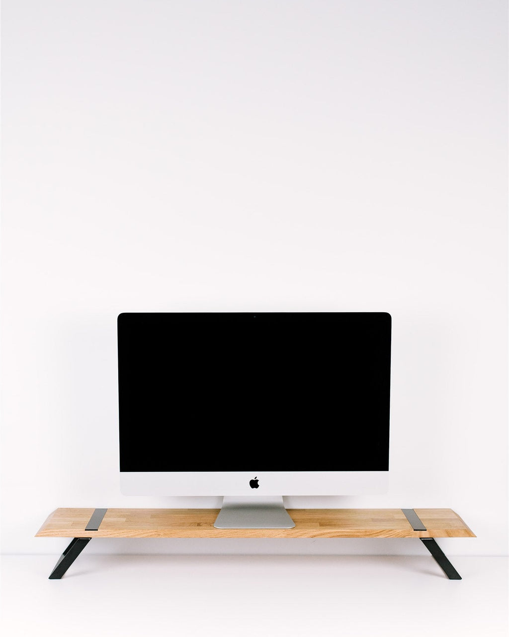 Computer monitor on a wooden stand against a white wall