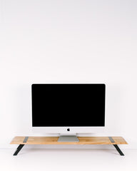 Computer monitor on a wooden stand against a white wall