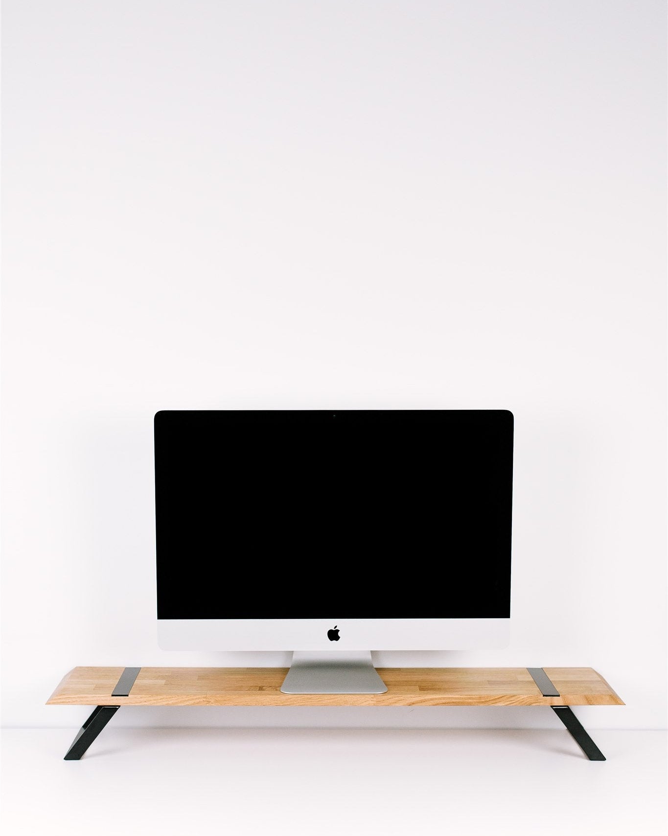 Computer monitor on a wooden stand against a white wall