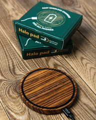 Wooden Halo pad wireless charger on a wooden surface with packaging in the background.