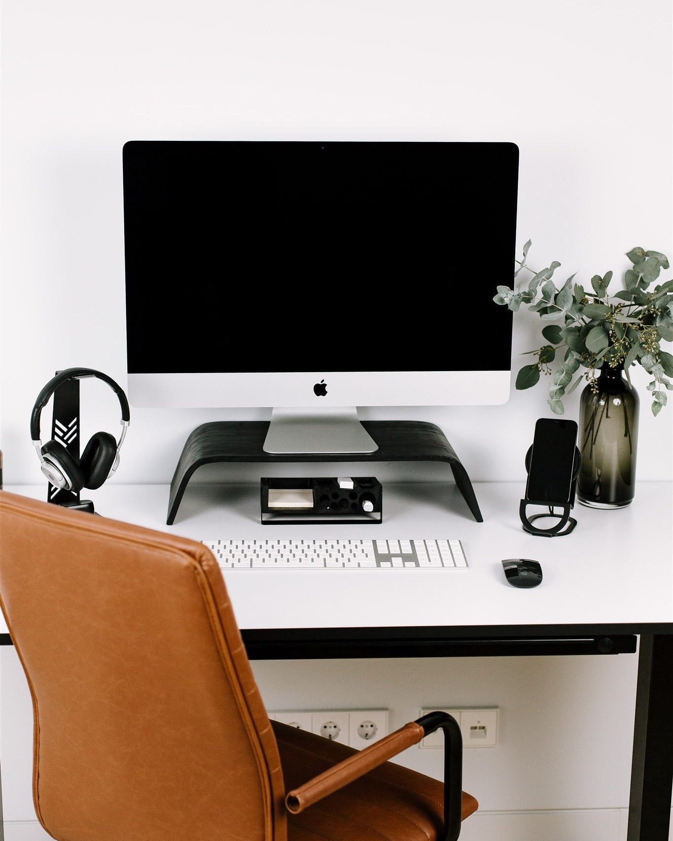 Modern home office setup with a desk, computer monitor, chair, and decorative elements.