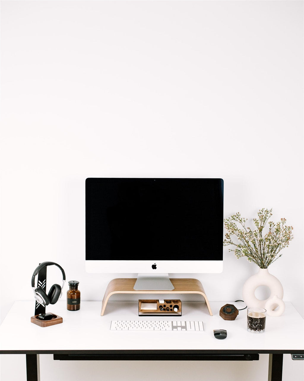 Modern home office desk with computer setup on a white wall background
