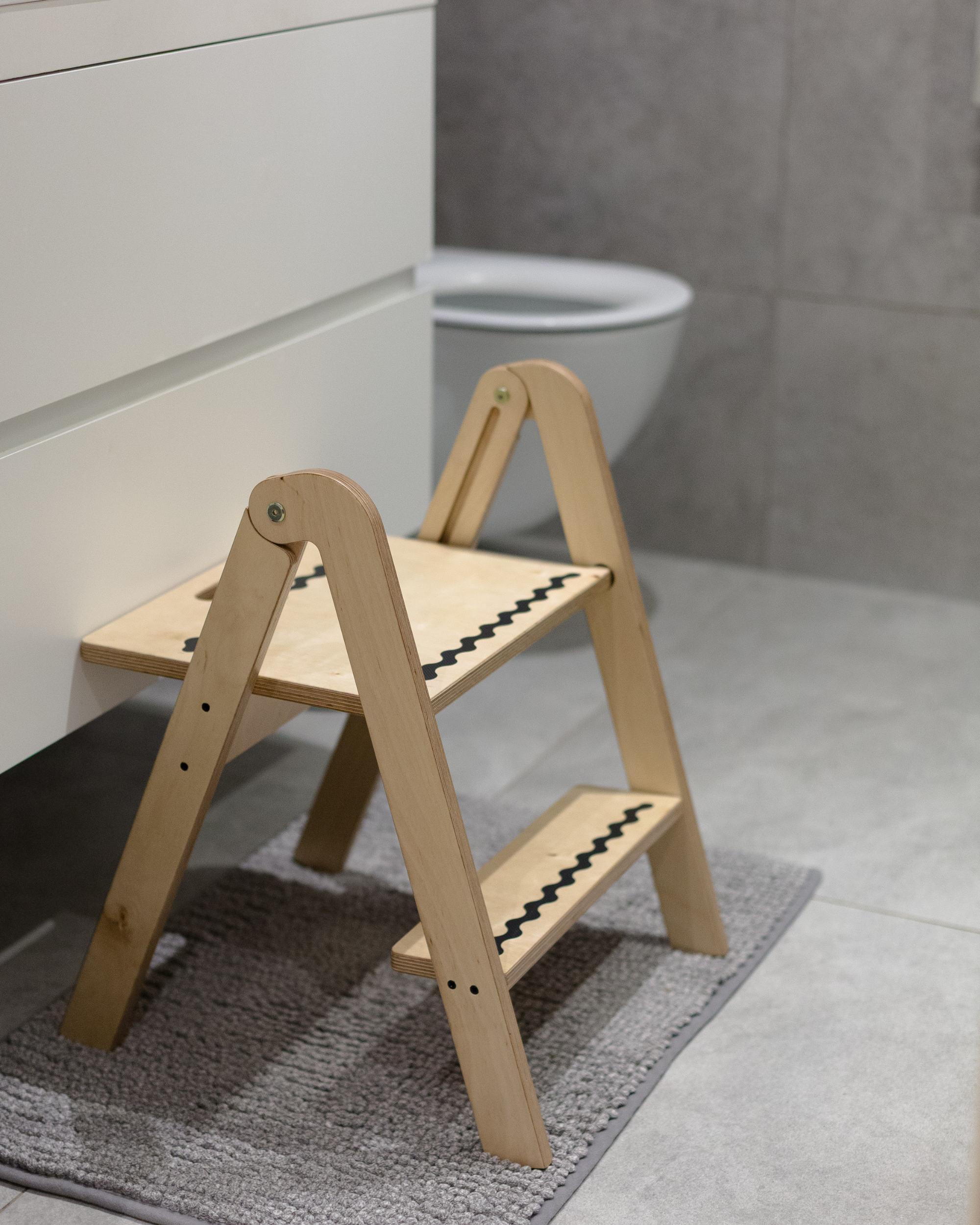 Wooden step stool on a bathroom floor with a toilet in the background