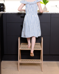 Person using a wooden step stool in a kitchen