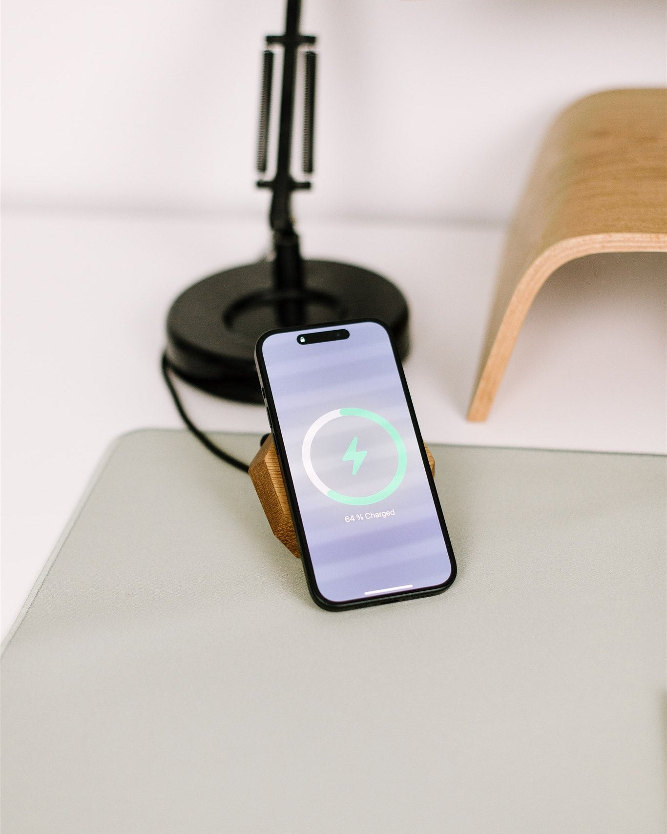 Phone on a wireless charger with a lamp and wooden object in the background
