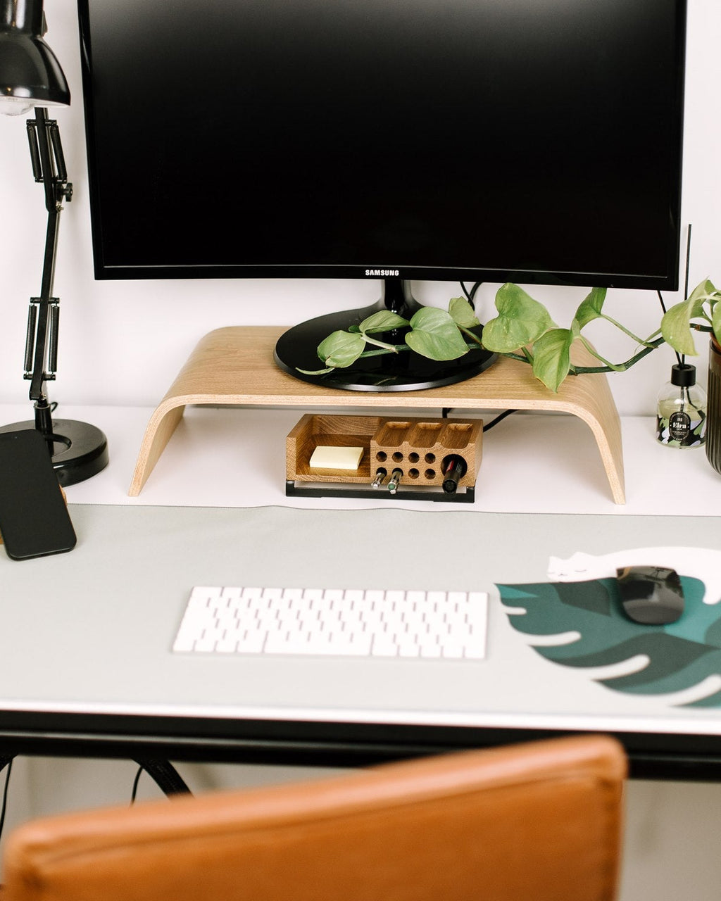 Home office setup with a computer monitor, keyboard, lamp, and decorative elements on a desk.