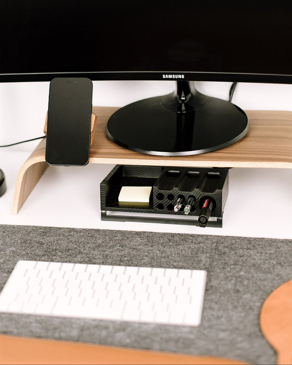 Samsung monitor on a wooden stand with a keyboard and mouse on a desk