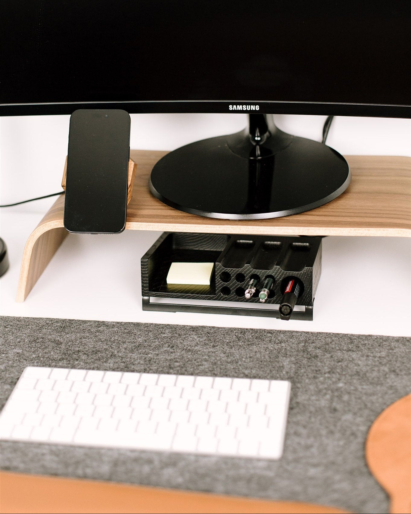 Samsung monitor on a wooden stand with a keyboard and mouse on a desk