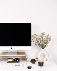 Modern office desk with computer monitor, keyboard, and decorative items on a white background