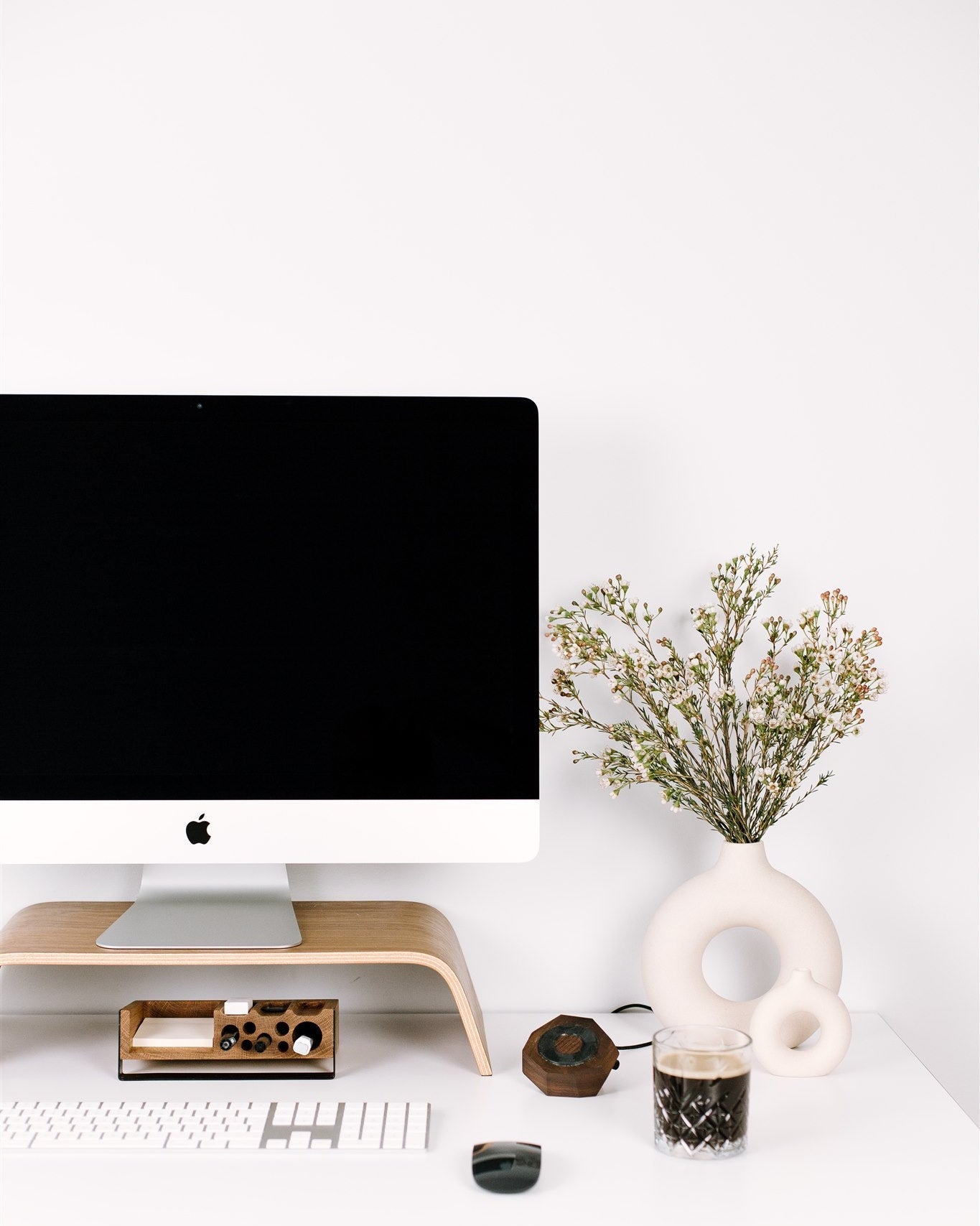 Modern office desk with computer monitor, keyboard, and decorative items on a white background