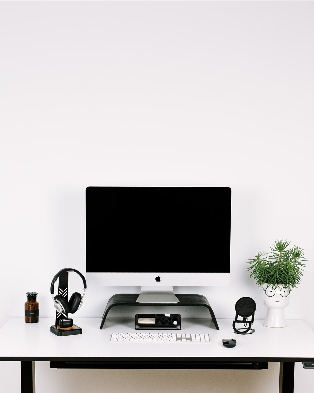 Modern office desk with computer setup against a white wall