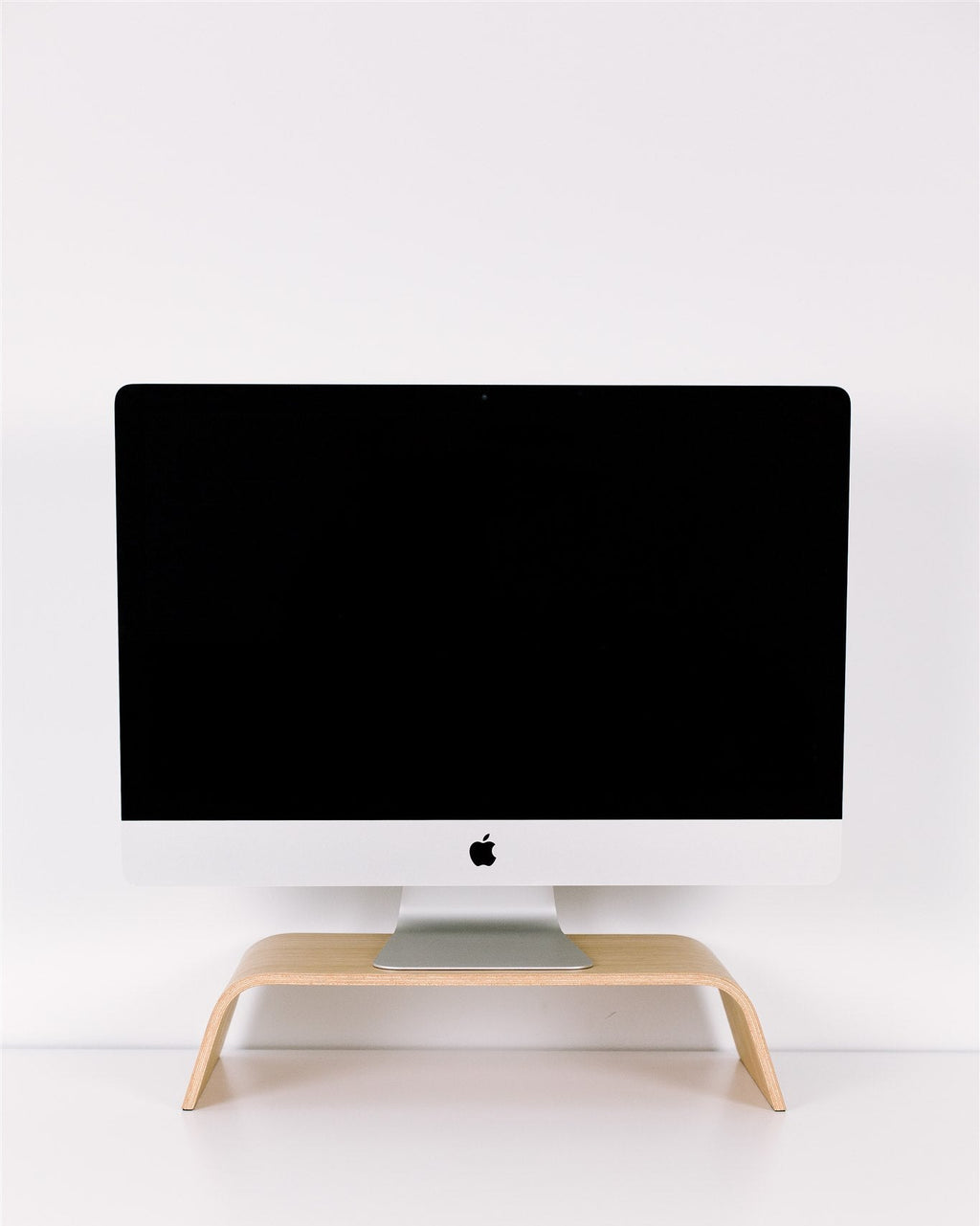 Black computer monitor on a wooden stand against a white wall