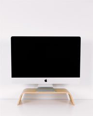 Black computer monitor on a wooden stand against a white wall