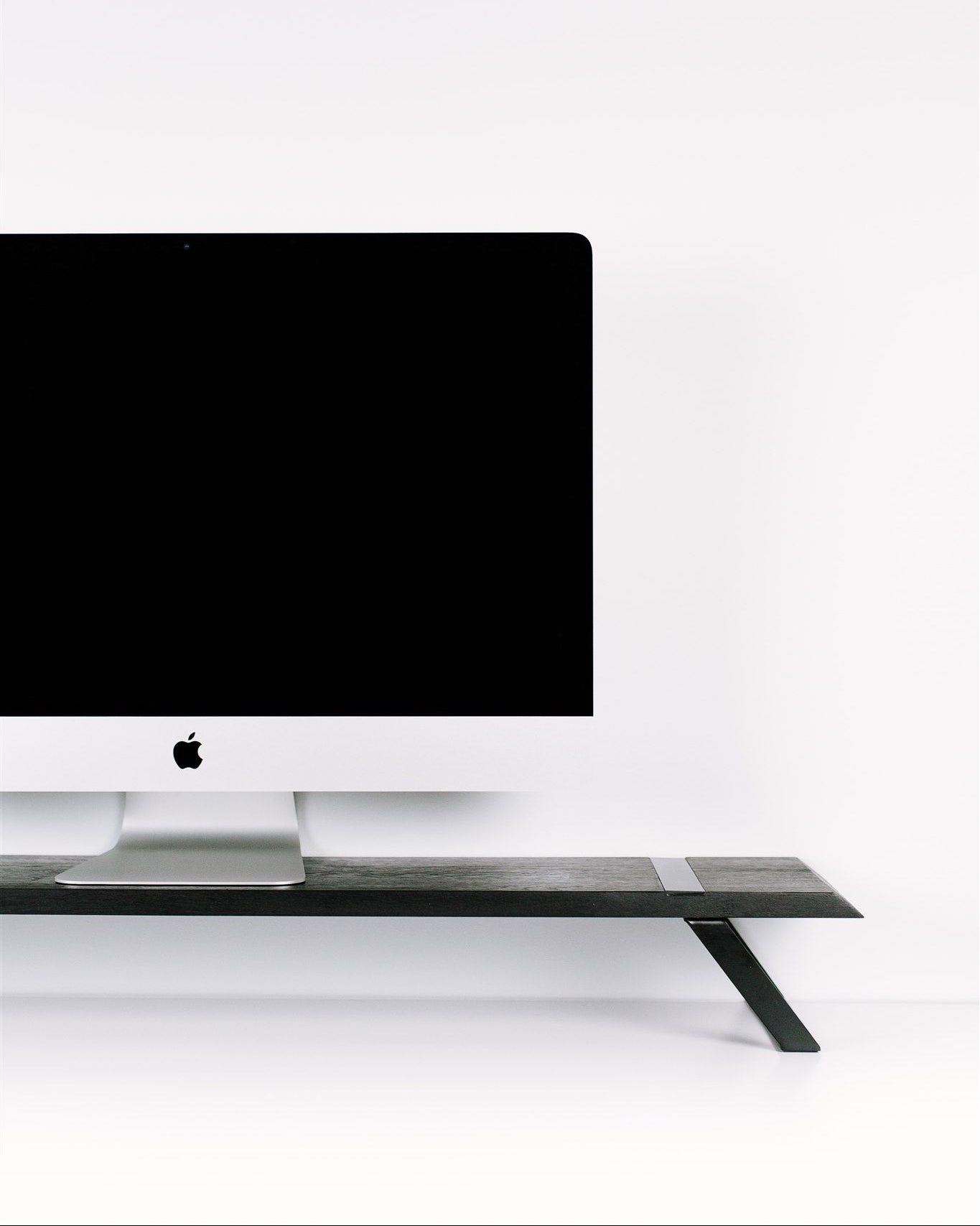 Black computer monitor on a white desk with a white wall background