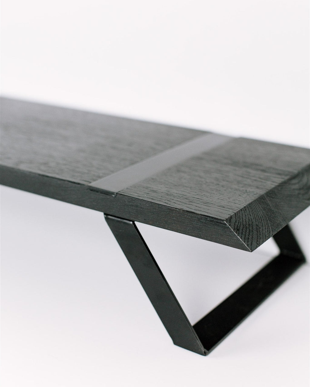 Modern black metal monitor stand with a wooden base on a white background