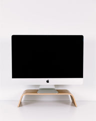 Computer monitor on a wooden stand against a white wall