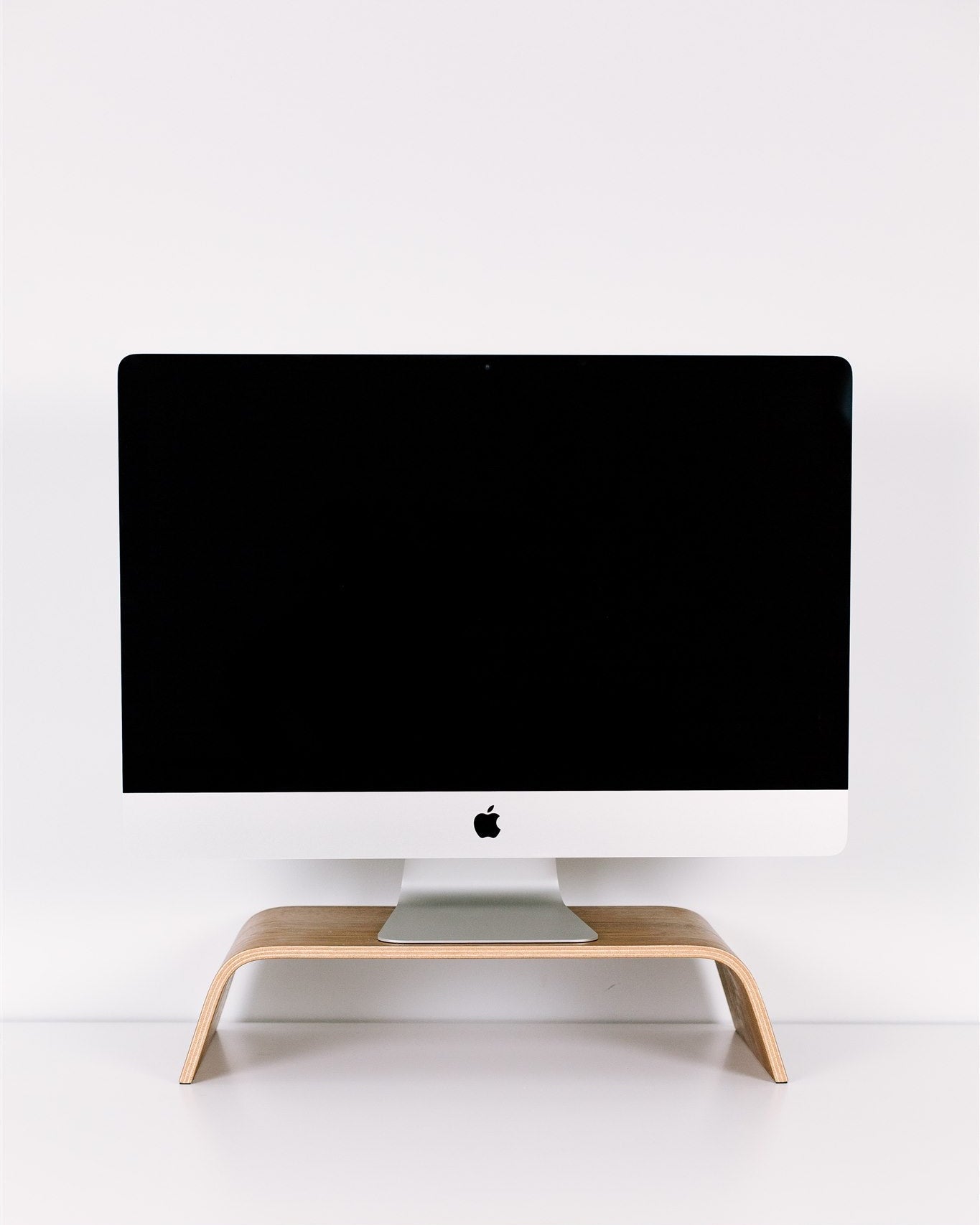 Computer monitor on a wooden stand against a white wall