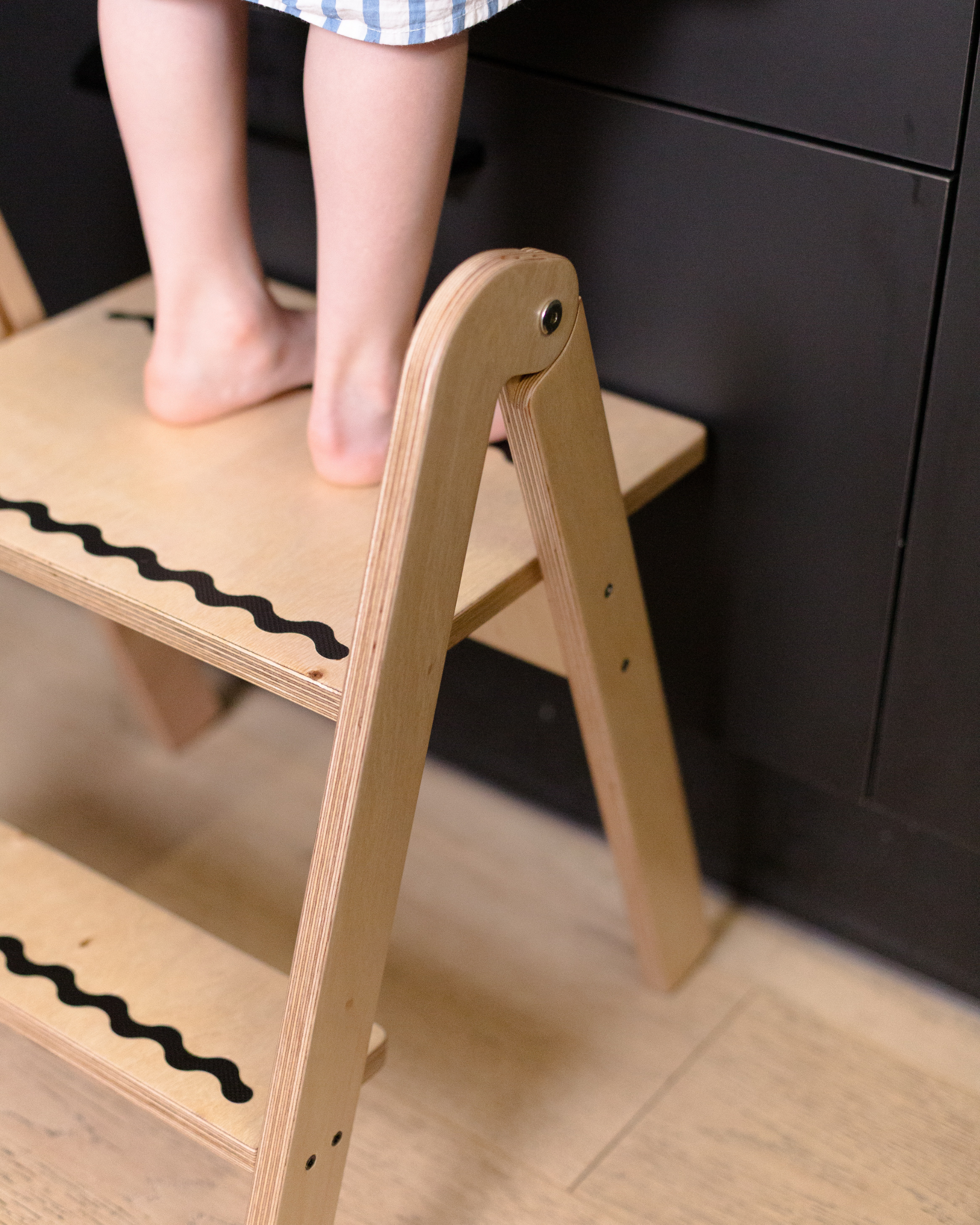 Child's feet on a wooden step stool with a dark background