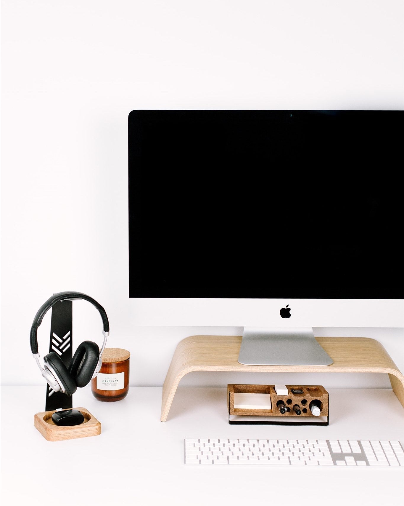 Modern office setup with a computer monitor, keyboard, and headphones on a white desk.