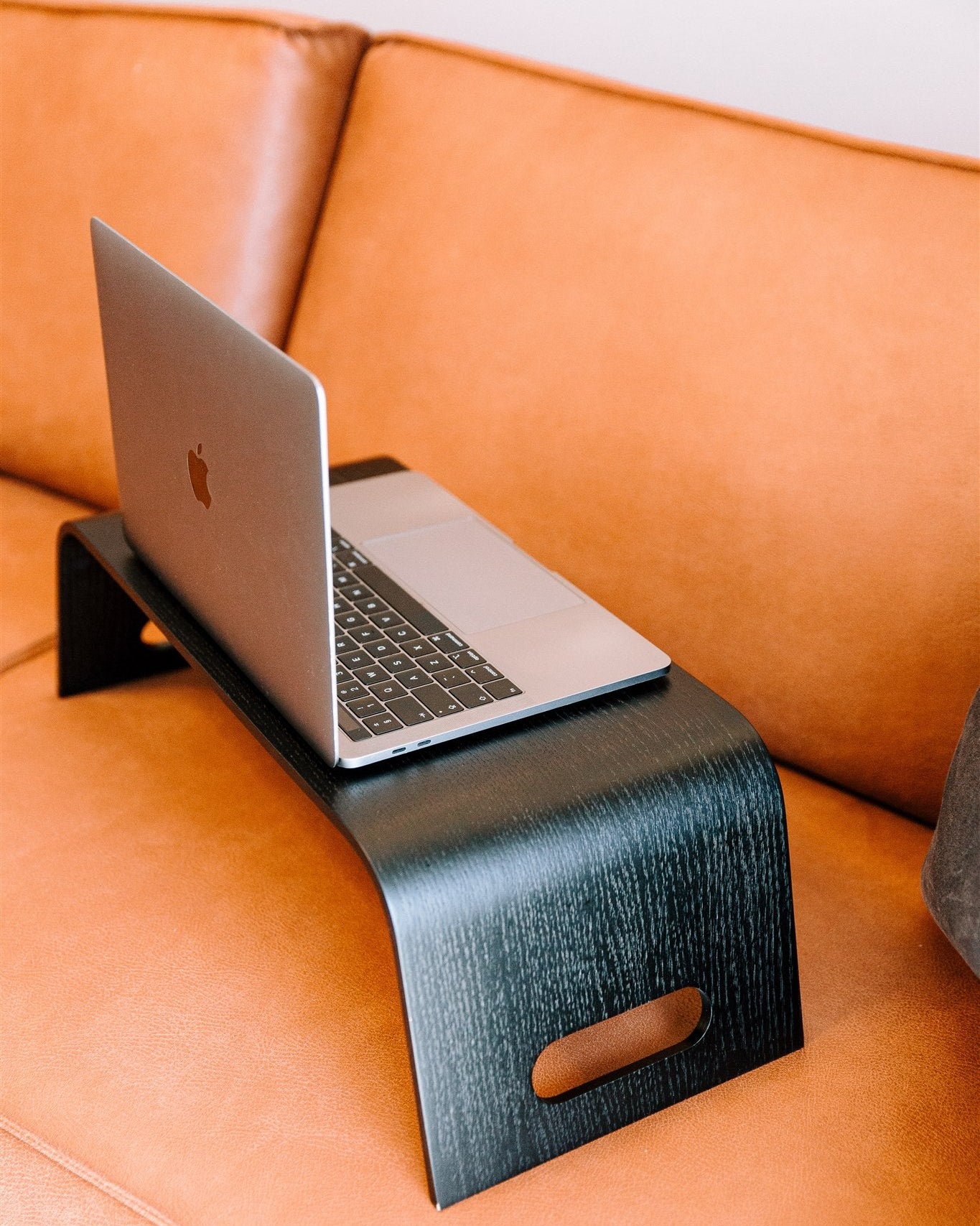 Laptop on a black stand on an orange couch