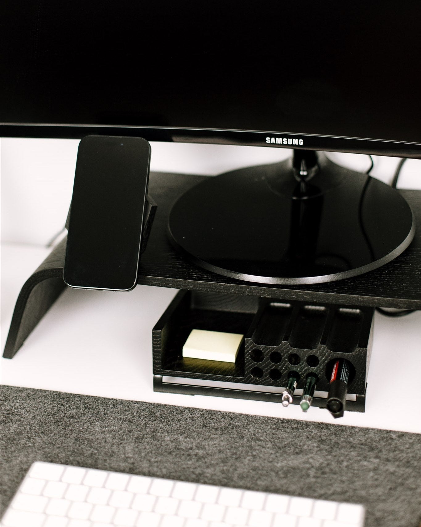 Samsung monitor on a desk with a phone and keyboard in the foreground