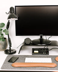 Modern office desk setup with computer monitor, lamp, and keyboard on a white surface.