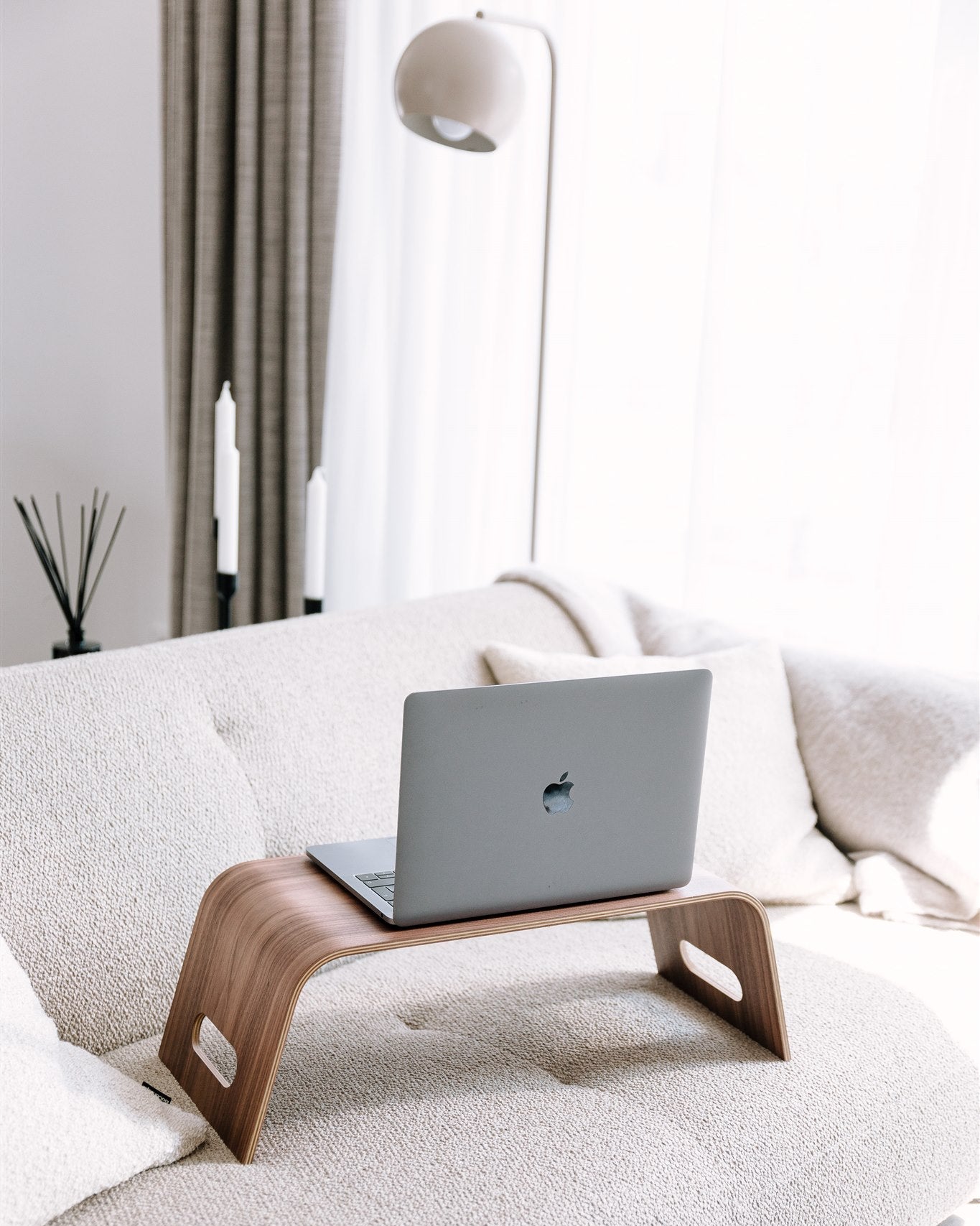 Laptop on a wooden stand on a sofa in a modern living room