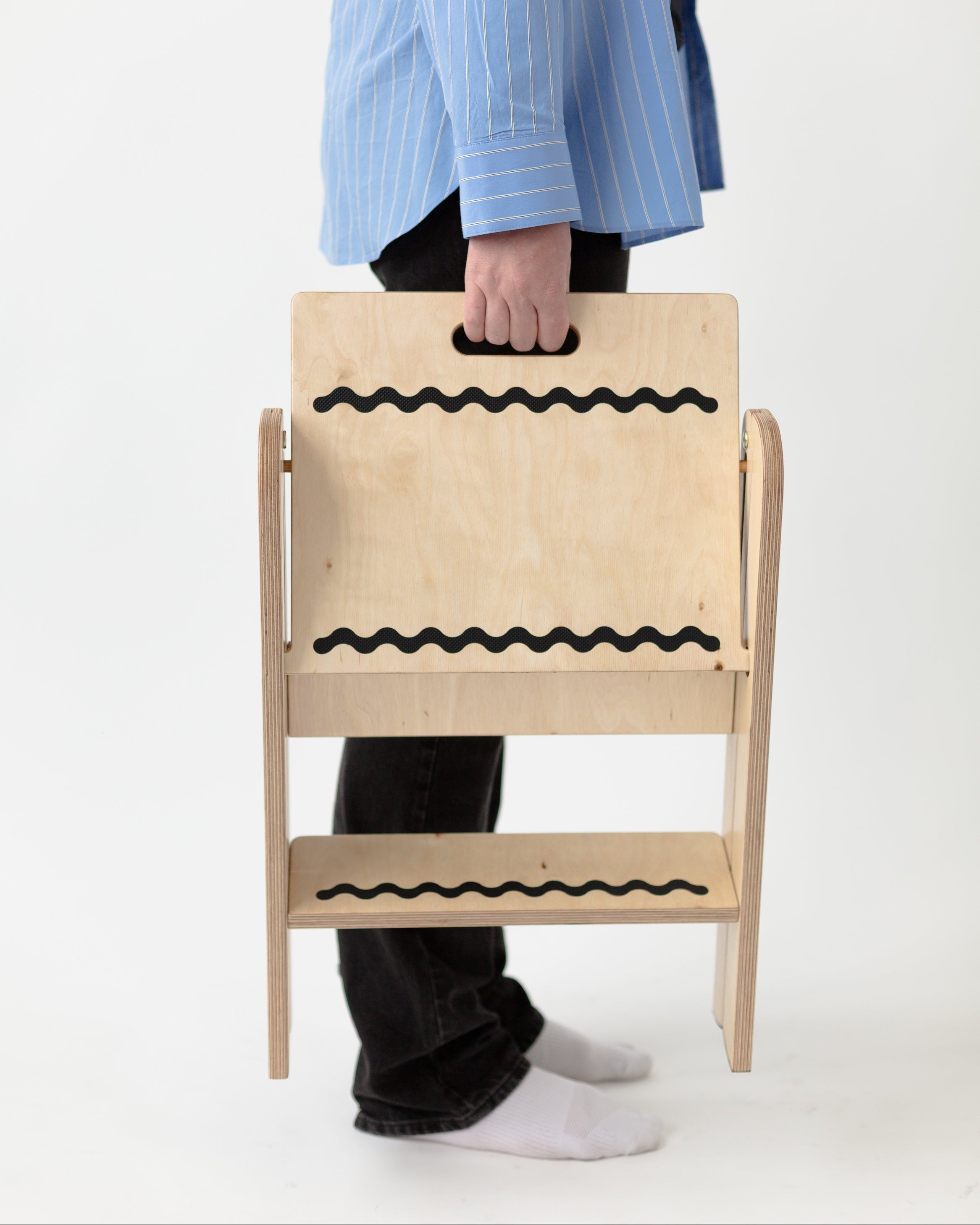 Person holding a beige step stool with black wavy lines on a white background
