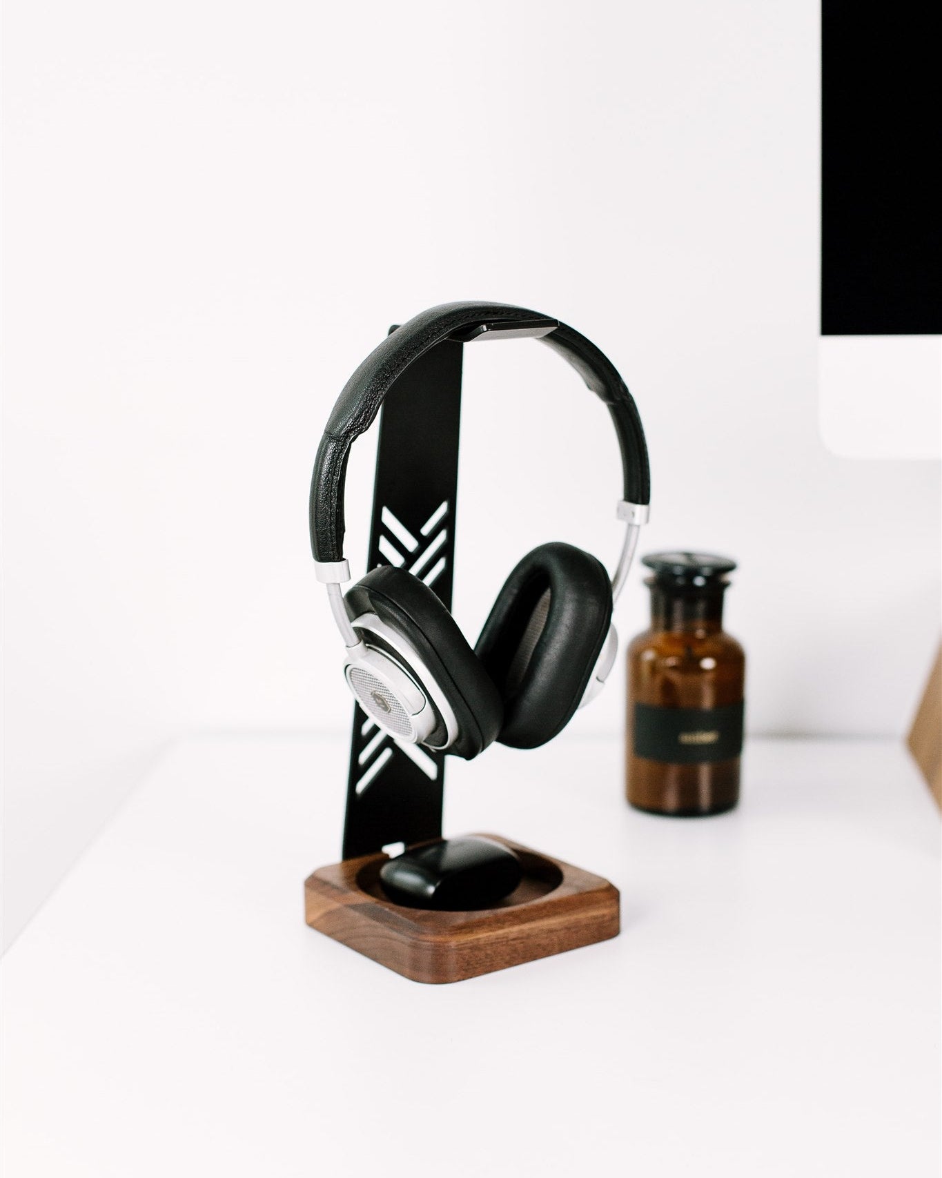 Black headphones on a wooden stand with a white background