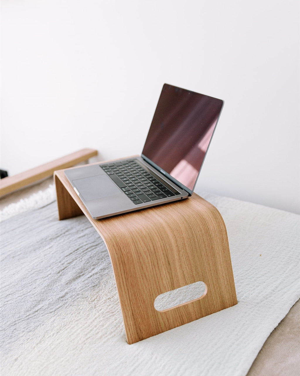 Wooden laptop stand with a laptop on a white surface