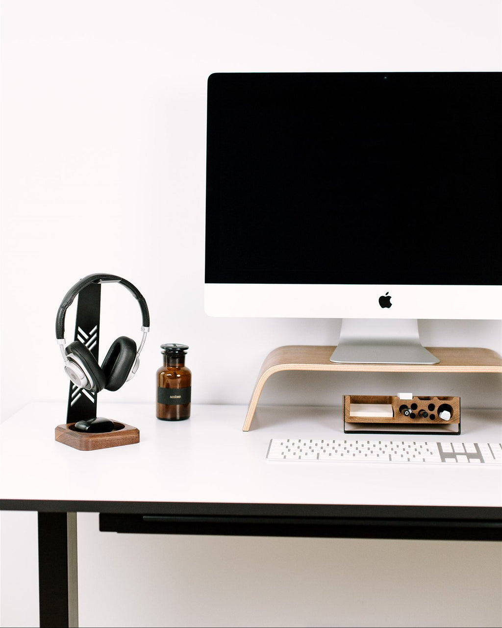 Modern desk setup with computer monitor, keyboard, and headphones on a white background