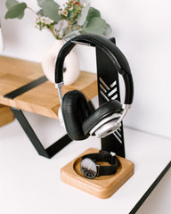 Black headphones on a wooden stand with a white background