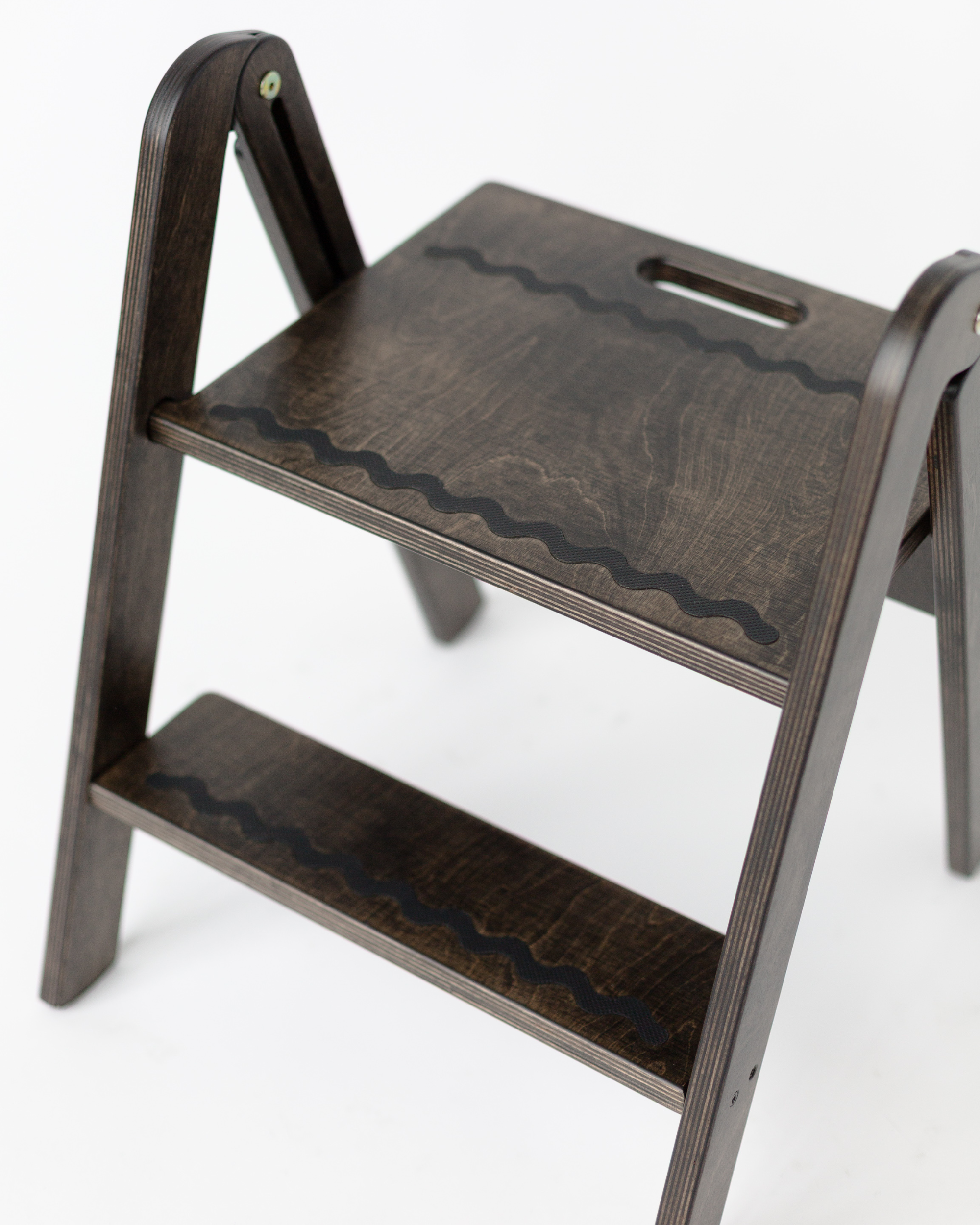 Wooden step stool with wavy pattern on a white background