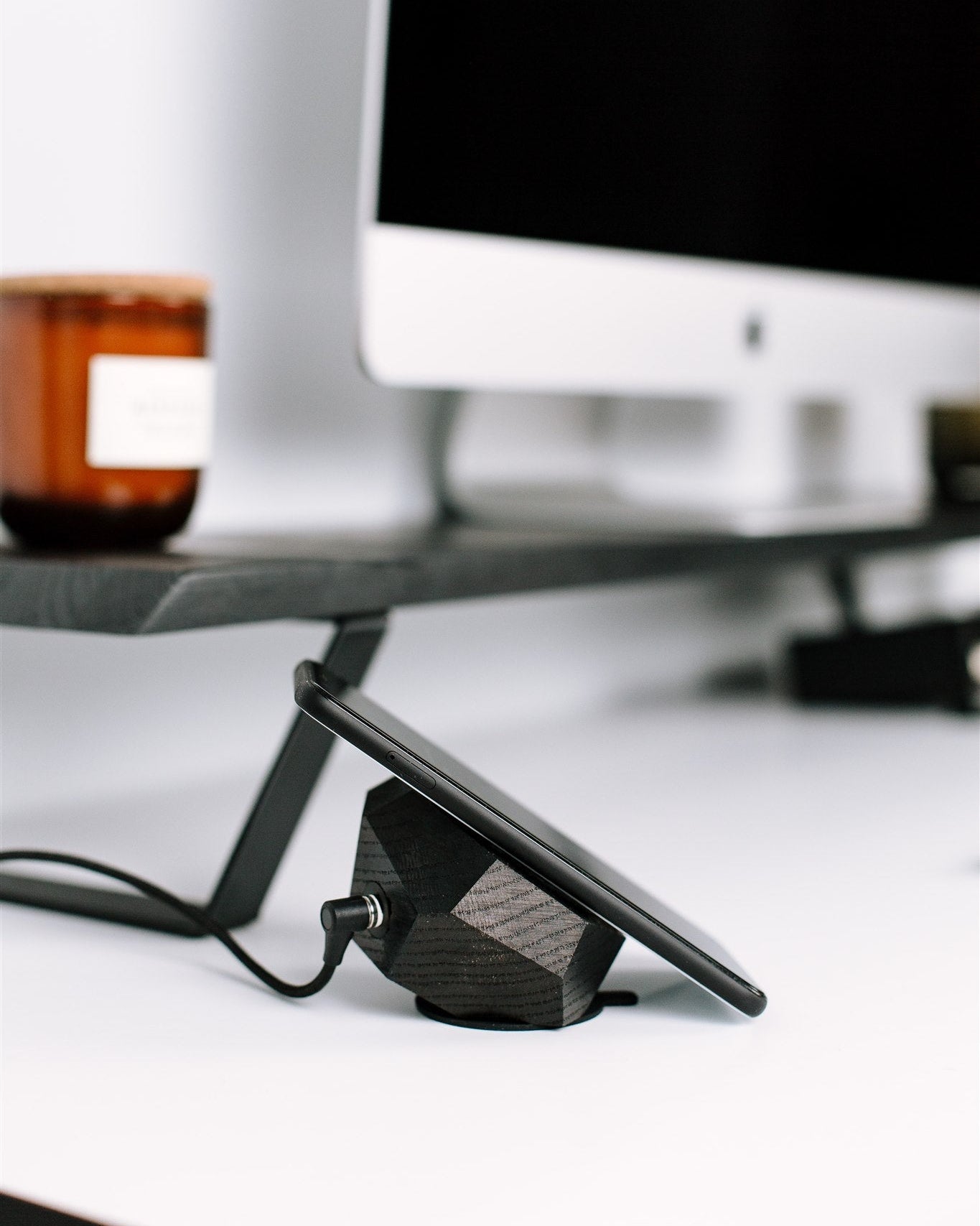 Black computer monitor stand on a desk with a computer screen in the background