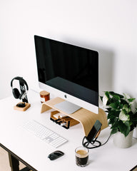 Modern office desk setup with computer monitor, keyboard, mouse, headphones, and a plant.
