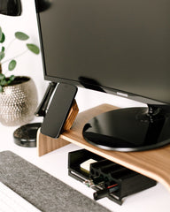Wooden monitor stand with a computer monitor and keyboard on a desk.